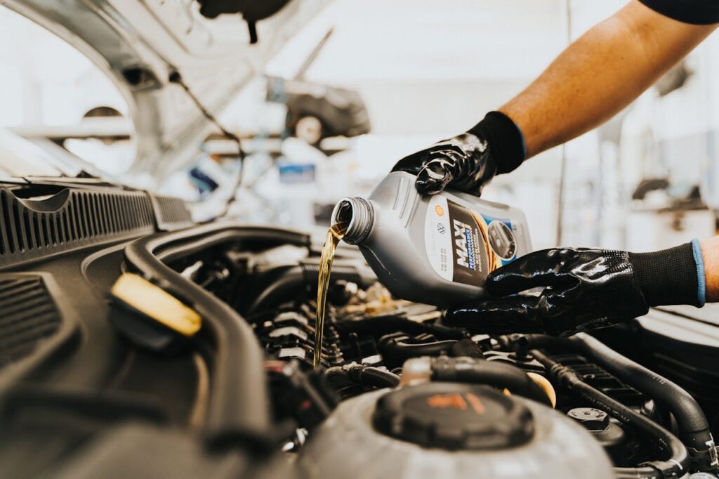 pexels photo 13065690 Close-up of a mechanic pouring engine oil into a car engine in an auto repair shop.