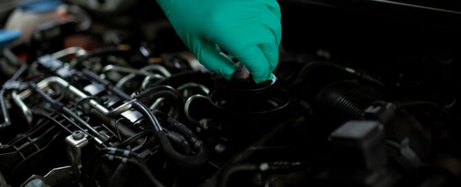 Gloved hand working on an engine during an oil change